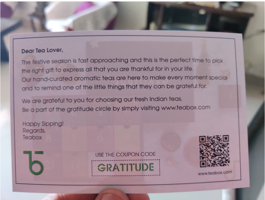 Hand holding a Teabox thank you card with the coupon code GRATITUDE