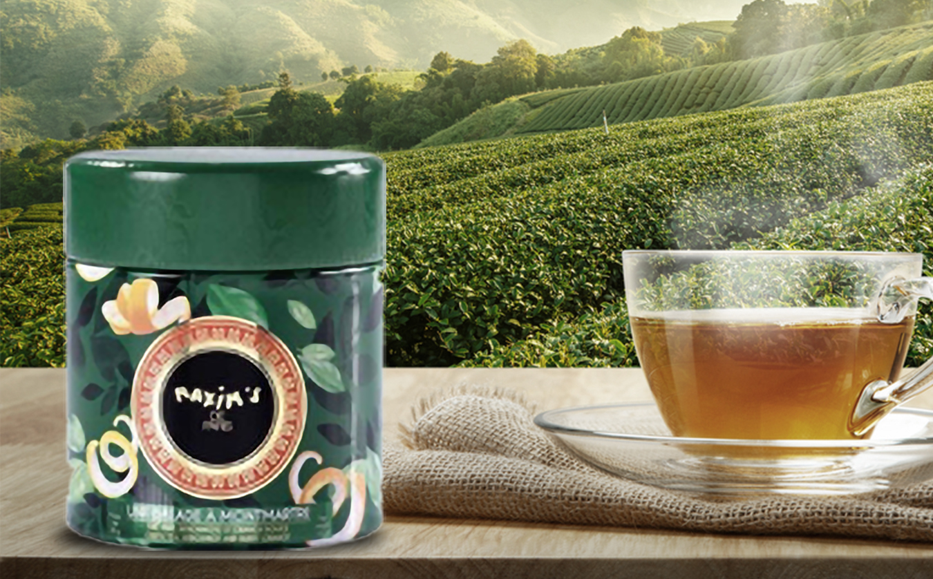 Maxim's tea tin next to a cup of tea