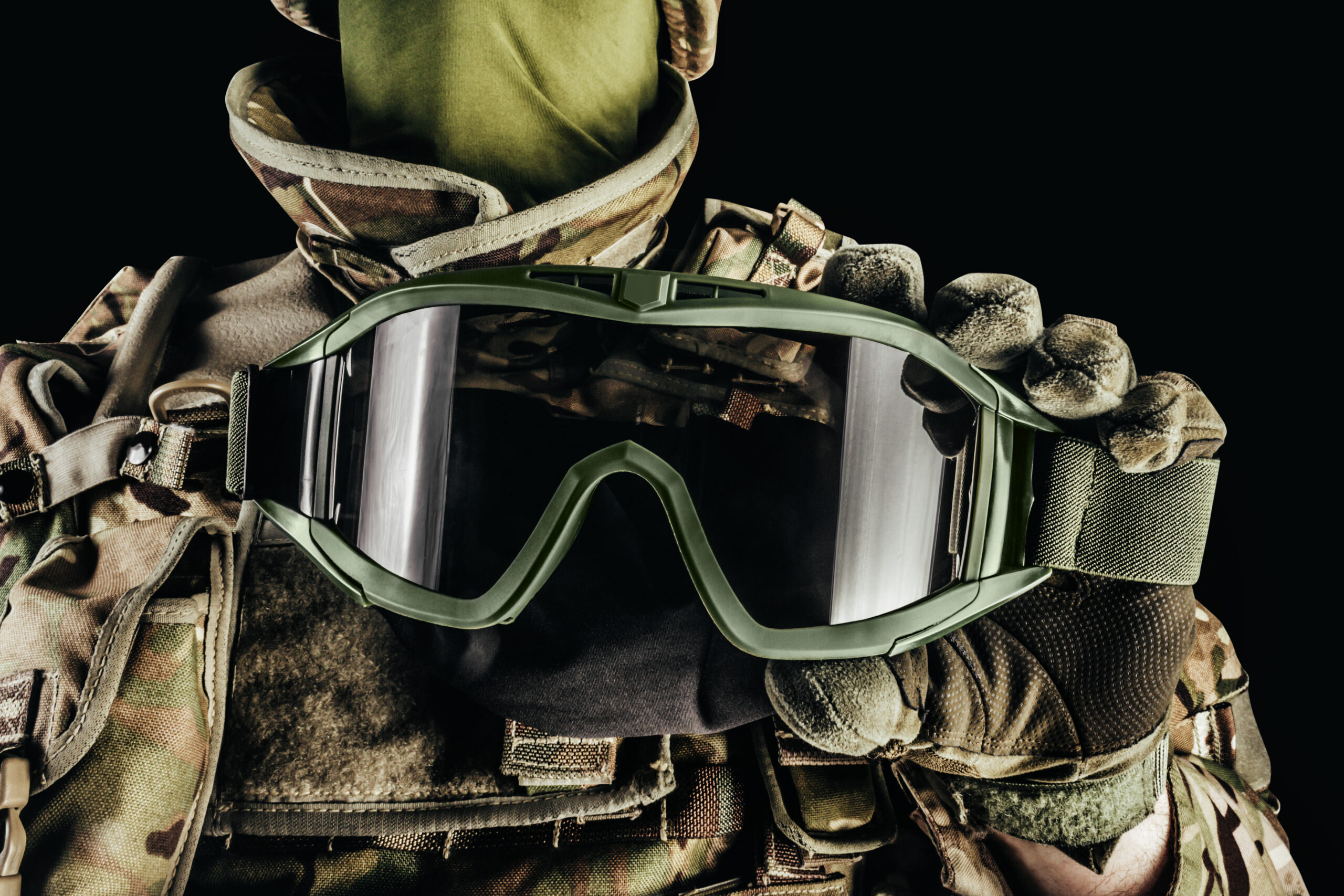 Soldier in an armored vest holding tactical goggles