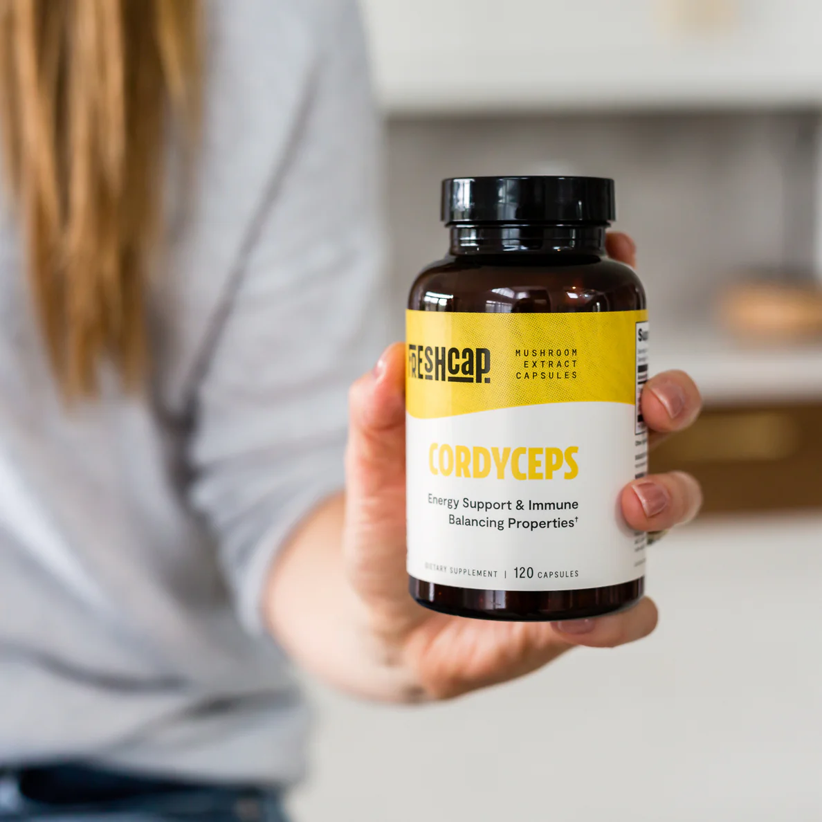 Hand holding a FreshCap Cordyceps capsule bottle