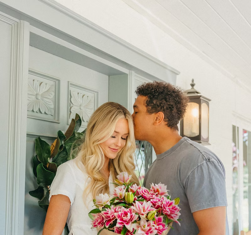 Couple holding a BloomsyBox bouquet at the front door