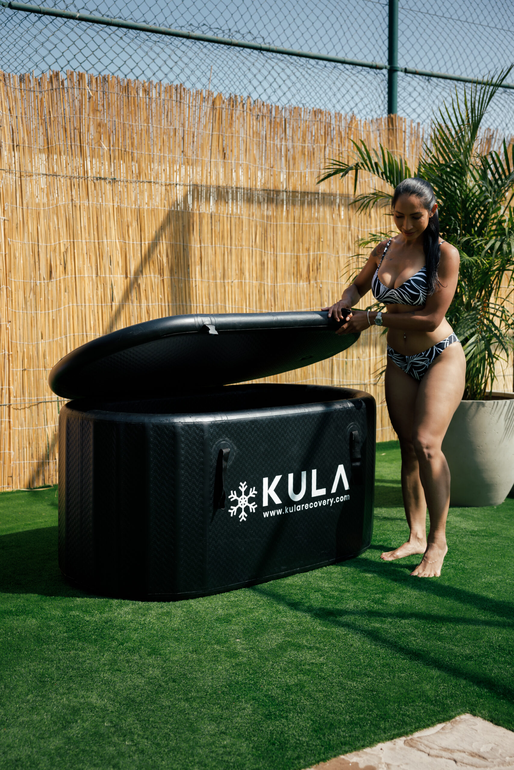 Woman opening a KULA cold plunge tub outdoors