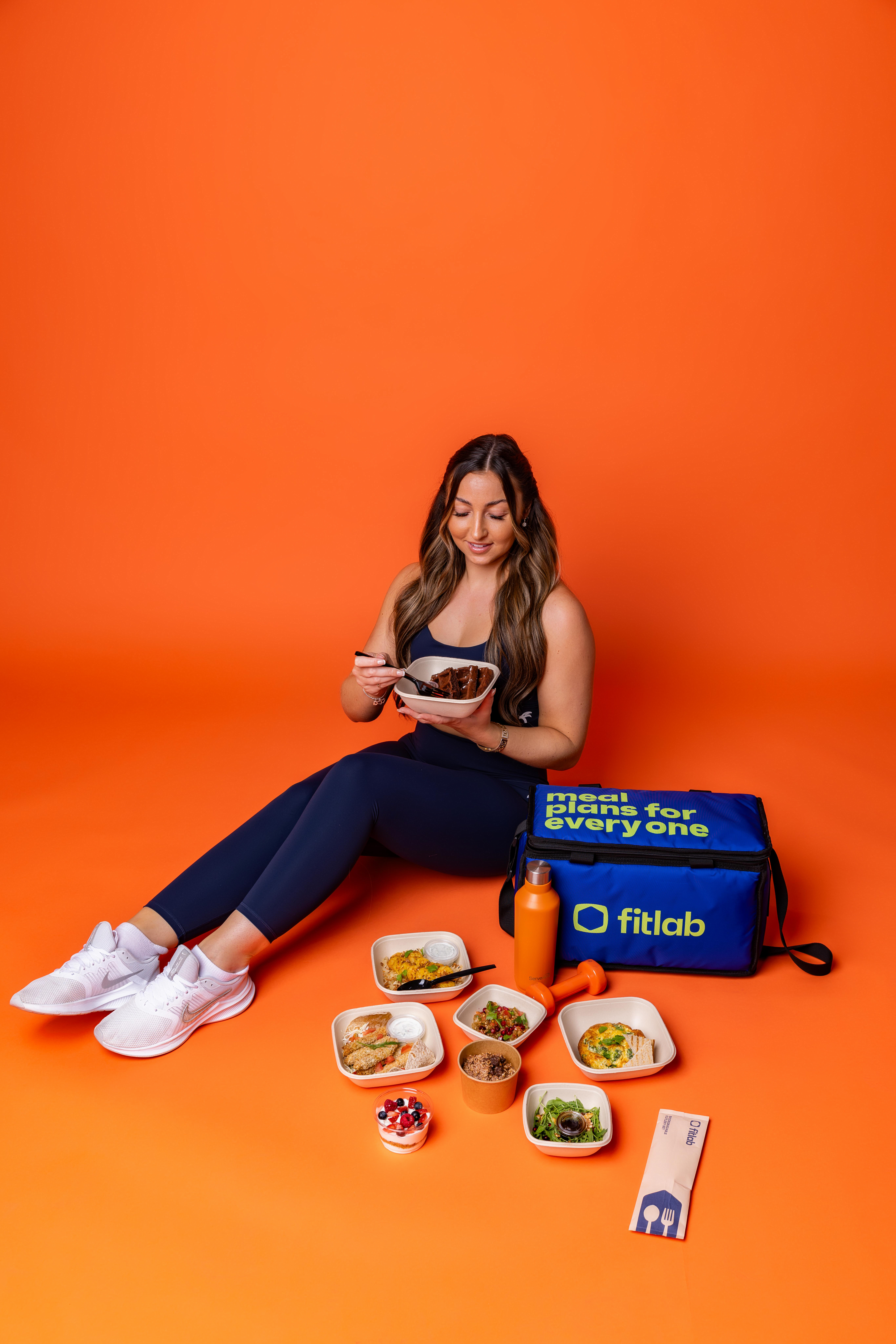 Woman eating from a Fitlab meal plan bag