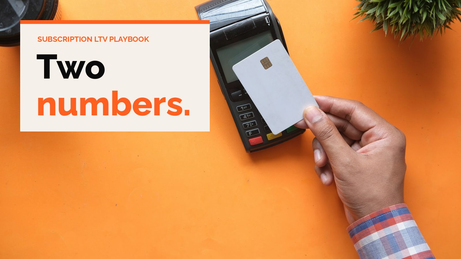 A hand holding a blank card over a card payment terminal on an orange table